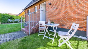 A brick house with a small outdoor seating area, including a table and two chairs. - Marienhüs - Cozy, central vacation apartment in Westerland for up to 2 (Sylt)