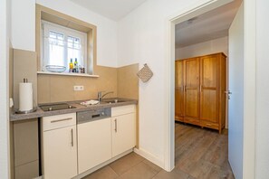 A compact kitchen with a window, a sink, and wooden cabinets.