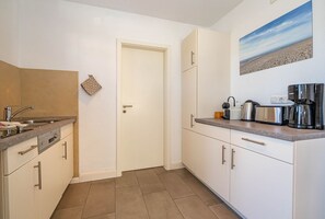 Eine kleine Küche mit Spüle, Herd und Geräte auf der Arbeitsfläche.