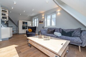 A modern loft apartment with a kitchen, dining area, and living room.
