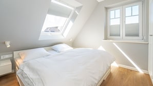 A bedroom with a skylight, a bed, a bedside table, and a window. - Sturmhaube - Apartment for max. 4 persons in Alt-Westerland with balcony. (Sylt)