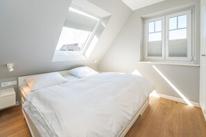 Une chambre avec un puits de lumière, un lit, une table de chevet et une fenêtre.