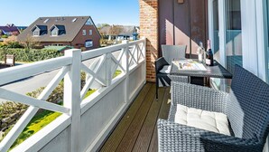 A balcony with wicker furniture, a table, and a bottle of wine. - Sturmhaube - Apartment for max. 4 persons in Alt-Westerland with balcony. (Sylt)