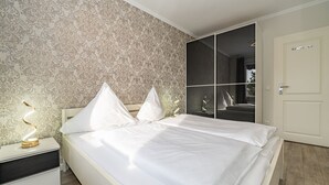 Ein modernes Schlafzimmer mit einem großen Bett, einem Nachttisch mit Lampe und einem Spiegel.