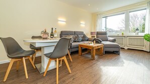 Ein modernes Wohnzimmer mit einem Esstisch, zwei grauen Sofas und einem Couchtisch.