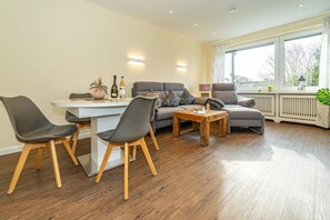 A modern living room with a dining table, two grey sofas, and a coffee table.