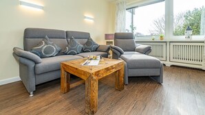 Ein Wohnzimmer mit grauem Sofa, grauem Sessel und Couchtisch aus Holz.