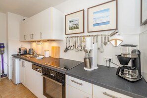 Eine moderne Küche mit weißen Schränken, einer schwarzen Arbeitsplatte, einer Kaffeemaschine und einem Wasserkocher.