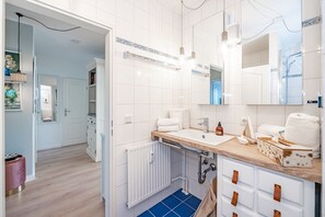 Une salle de bain moderne avec des carreaux blancs, un meuble-lavabo en bois, un évier et un miroir.