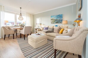Ein modernes Wohnzimmer mit einer Couch, Sesseln, einem Couchtisch und einem Essbereich.