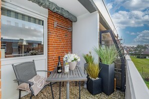 Un balcon avec une table, des chaises, une bouteille et des plantes en pot.