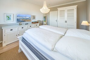 Ein Schlafzimmer mit einem großen Bett, weißen Möbeln und Bildern an der Wand.