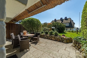 A patio with wicker furniture and a stone wall.