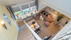 A spacious loft-style living area with a large window, a cozy seating area, and a staircase leading to an upper level.