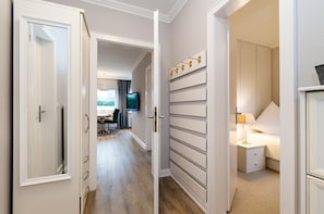 Ein Flur mit Essbereich, einem an der Wand montierten Fernseher und einem Schlafzimmer mit Bett und Nachttisch.