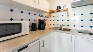 A kitchen with white cabinets, a microwave, a coffee maker, and a sink. - Seestern - Maritime Wohnung mit Meerblick und Balkon (Sylt)