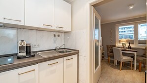 Una cocina moderna con armarios blancos, una máquina de espresso integrada y un lavamanos.