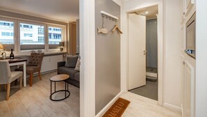 Habitación de hotel con zona de comedor, sofá, mesita redonda y ducha, con vista a la ciudad.