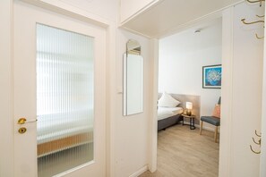 A hotel room with a bed, bedside table, chair, and a painting on the wall.