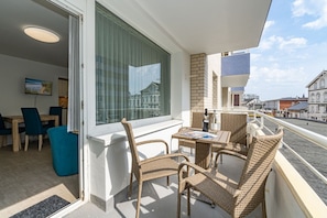 A balcony with wicker furniture, a dining area with a TV, and a view of the cityscape.