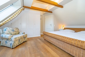 A bedroom with a large bed, a chair, a wardrobe, and a skylight. - Üüs Lek - Neu!!! Ab Januar 2023 in Unserer Vermittlung. Sehr Gemütliche 2 Zimmerwohnung für max 4 (Sylt)