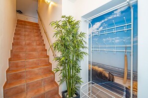 A staircase with terracotta tiles, a bamboo plant, and a wall-mounted coat rack with hooks. - Üüs Lek - Neu!!! Ab Januar 2023 in Unserer Vermittlung. Sehr Gemütliche 2 Zimmerwohnung für max 4 (Sylt)
