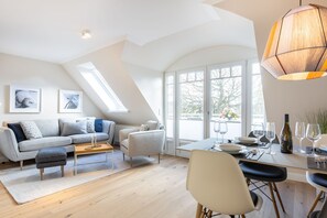 A modern loft apartment with a dining area, a sofa set, and a dining table set for two.