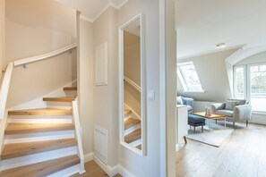 A modern interior with a wooden staircase, a living area with a sofa and a coffee table, and a skylight.