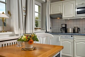 Een keuken met witte kasten, een houten tafel en een bloemenvaas.