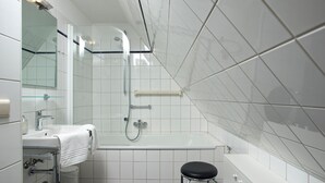 A modern bathroom with a glass shower enclosure, a white sink with a towel, and a black stool. - Witt Hingst App. 10 - Cozy 2-room vacation apartment, quietly situated with (Sylt)