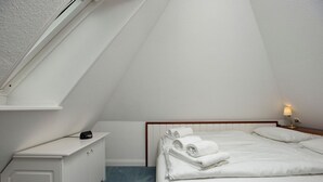 A small, clean room with a bed, a bedside table, and a nightstand. - Witt Hingst App. 10 - Cozy 2-room vacation apartment, quietly situated with (Sylt)