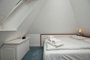Une petite chambre propre, avec un lit, une table de chevet et une commode.