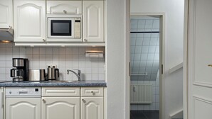 Uma cozinha com armários brancos, micro-ondas Bosch, lava-louças Siemens e máquina de café.