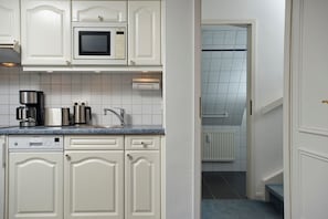 Een keuken met witte kasten, een Bosch magnetron, een Siemens vaatwasser en een koffiezetapparaat.