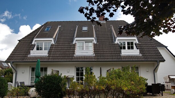 A two-story house with a sloped roof, dormer windows, and a stone foundation. - Witt Hingst App. 10 - Cozy 2-room vacation apartment, quietly situated with (Sylt)
