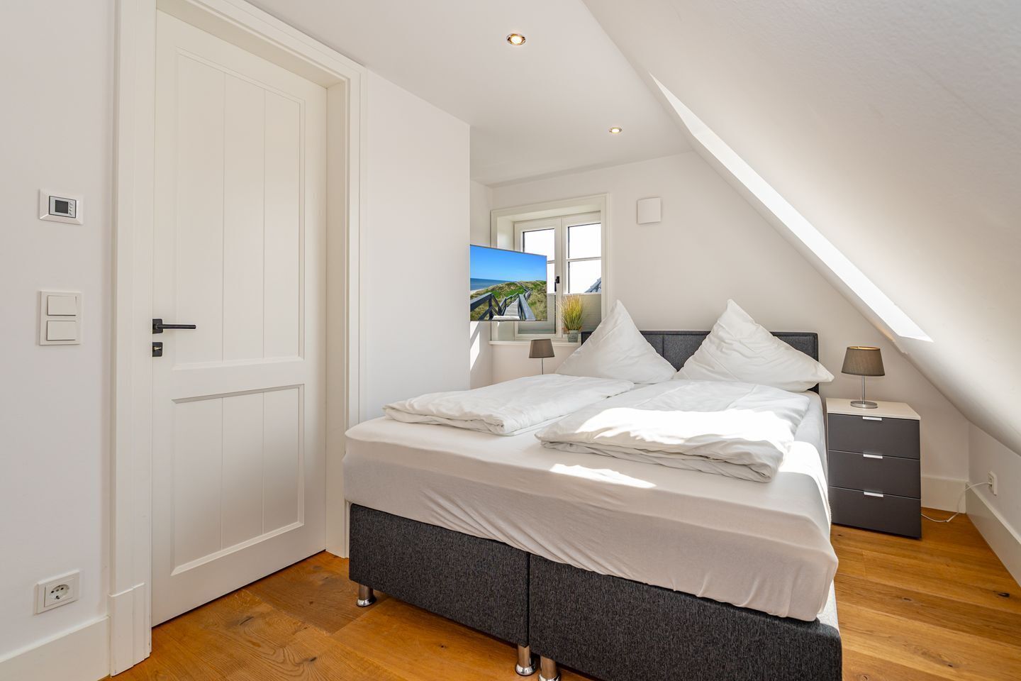 A bedroom with a bed, bedside table, and a window with a view.
