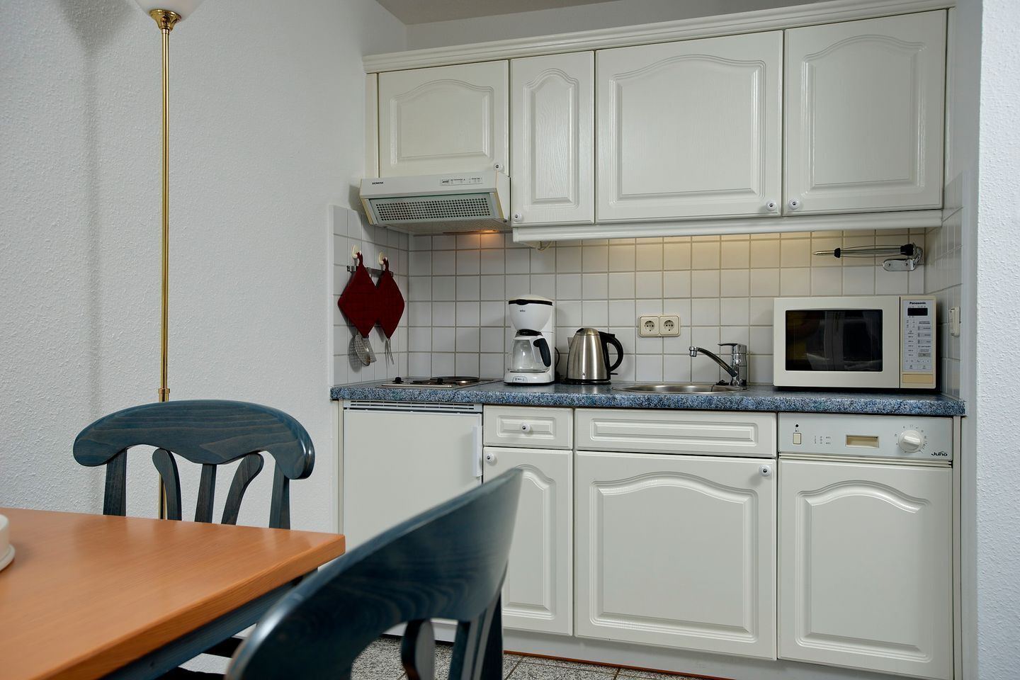 A kitchen with white cabinets, a microwave, a coffee maker, and a sink.