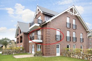 Un immeuble à plusieurs étages, construit en briques, avec un toit à pignon et des fondations en pierre.