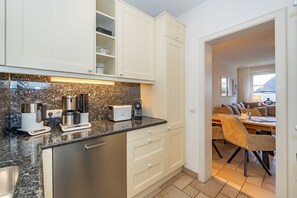 A modern kitchen with granite countertops, white cabinetry, and a dining area with a table and chairs.
