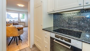 Eine Küche mit weißen Schränken, einer Granit Arbeitsplatte und einem eingebauten Backofen.