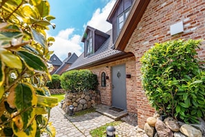 Ein Backsteinhaus mit einem Kiesweg, einer grauen Tür und einem kleinen Garten.