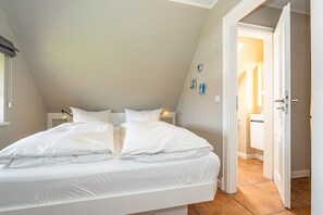 Un dormitorio con una cama grande, una mesita de noche y una puerta que da al baño.