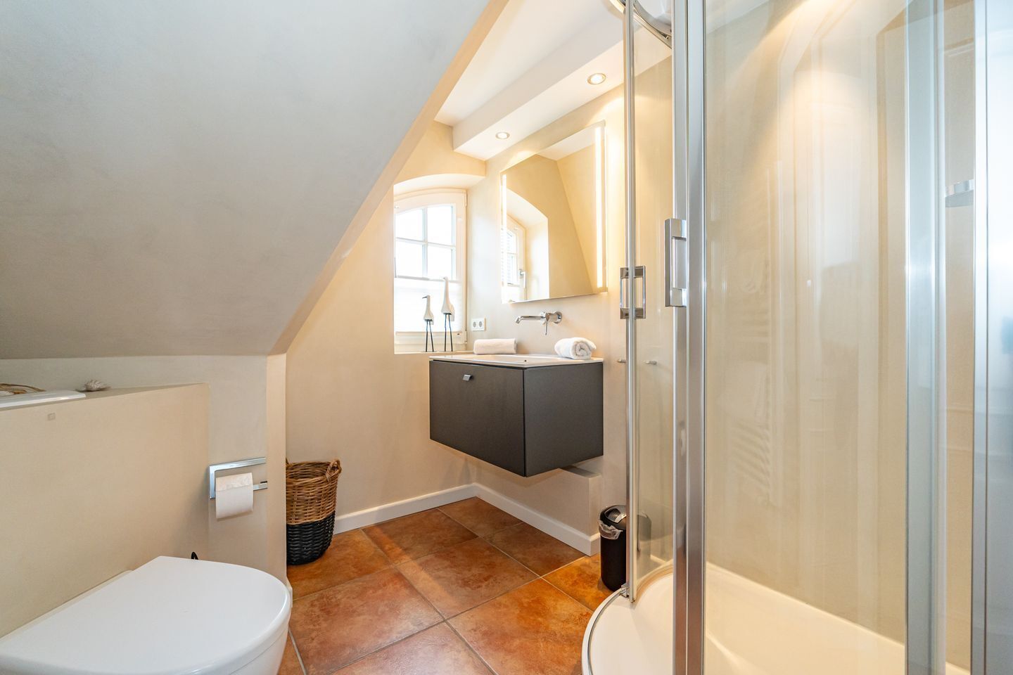 A modern bathroom with a shower, toilet, and sink.