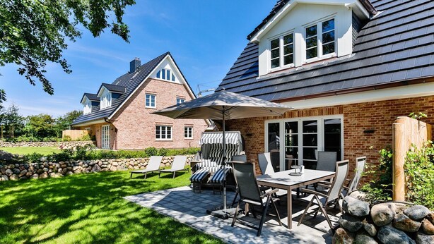 A patio with a table and chairs, a barbecue grill, and a stone wall.