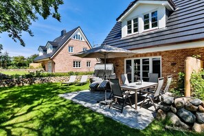 Une terrasse avec une table et des chaises, un barbecue et un mur en pierre.