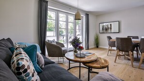 A modern living room with a sofa, chairs, a coffee table, and a dining area.