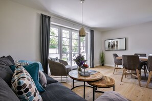 A modern living room with a sofa, chairs, a coffee table, and a dining area.