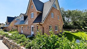A row of brick houses with pitched roofs and a well-maintained garden.