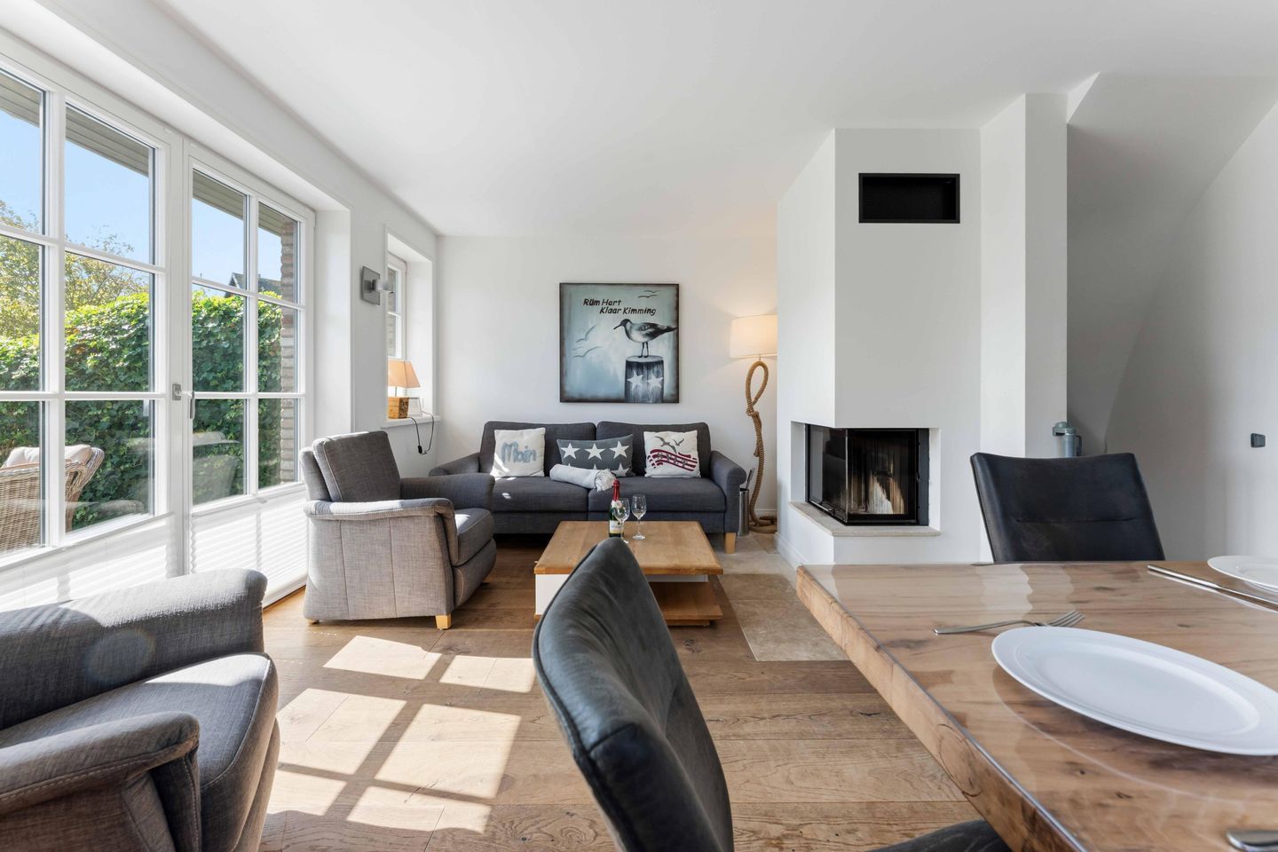 A modern living room with a fireplace, a dining table, and a sofa set.