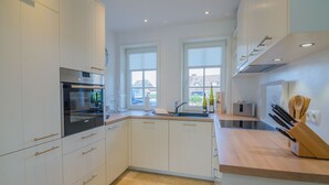Una cocina moderna con armarios blancos, horno integrado, un lavabo y encimera de madera.